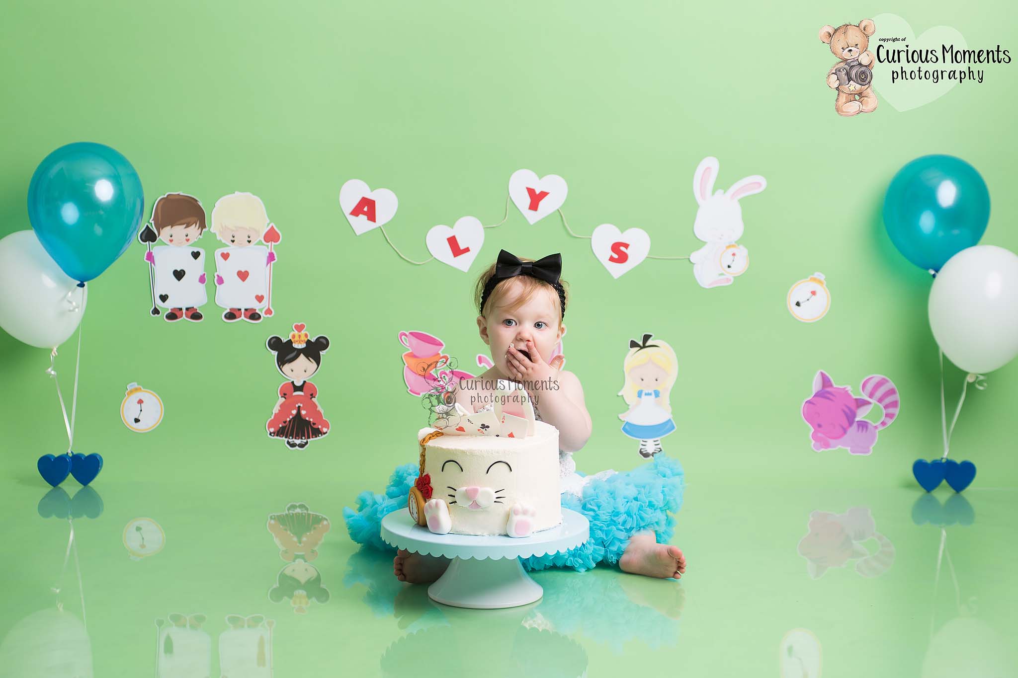 baby girl eating cake during her Alice in wonderland themed cake smash