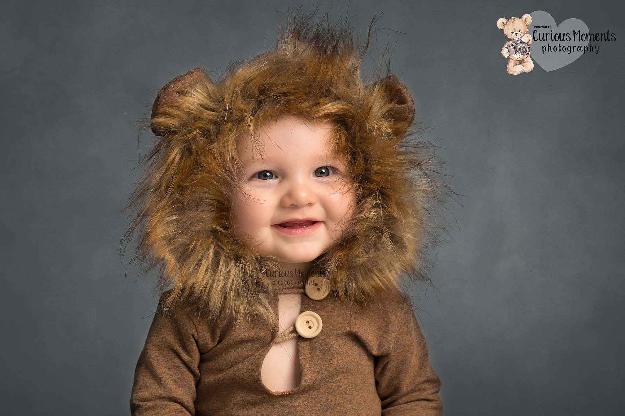 Clsoe up image of baby boy wearing a brown bear outfit on a grey background during his photo shoot in carmarthenshire