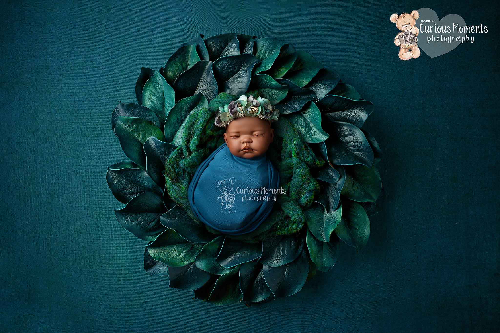 Ethnic baby girl in teal floral crown lying in a large flower