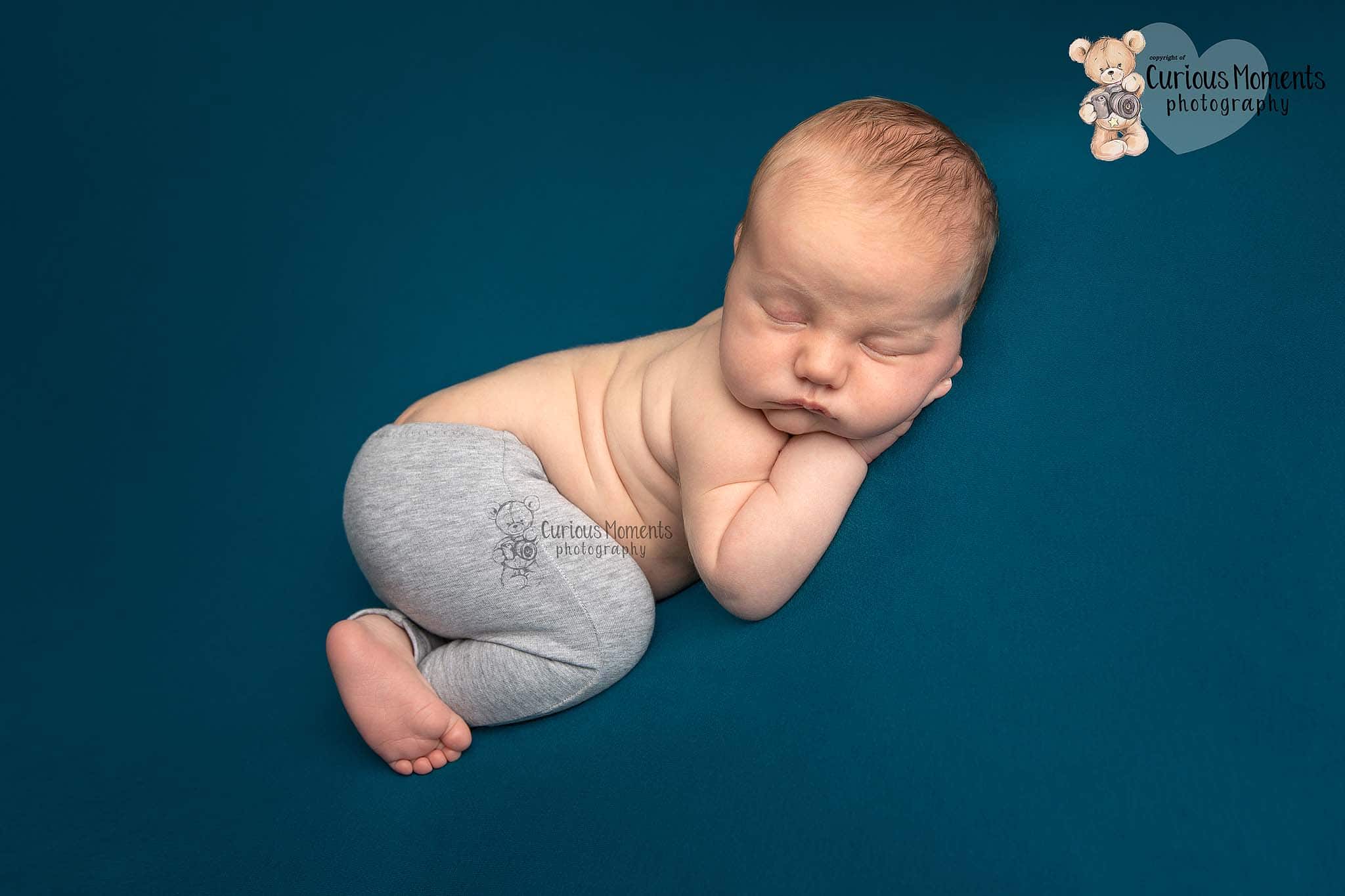 newborn baby boy in bum up pose on teal backdrop